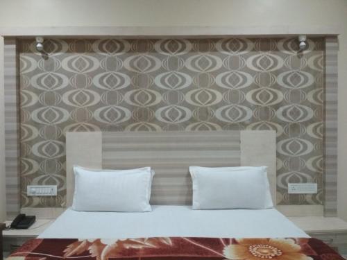 a bed with two pillows in a bedroom with a wall at Pachmarhi Shri Krishna Hotel in Pachmarhī