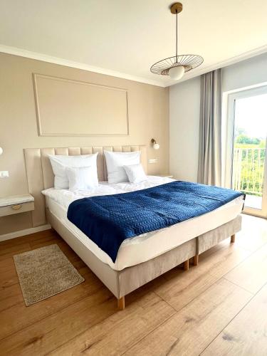 a bedroom with a large bed with a blue blanket at Jaśminowe Wzgórze Apartamenty blisko plaży in Władysławowo
