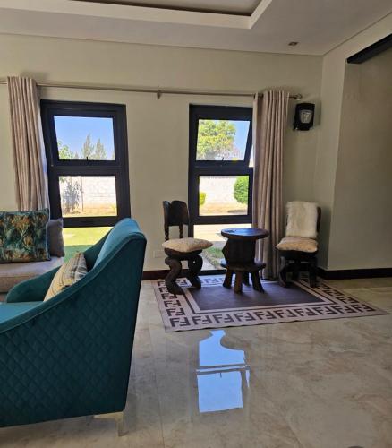 a living room with a couch and chairs and windows at Chuumba Villas in Lusaka