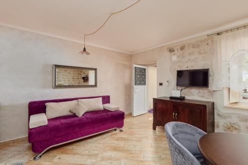 a living room with a purple couch and a tv at Konoba 224 Apartments in Kotor