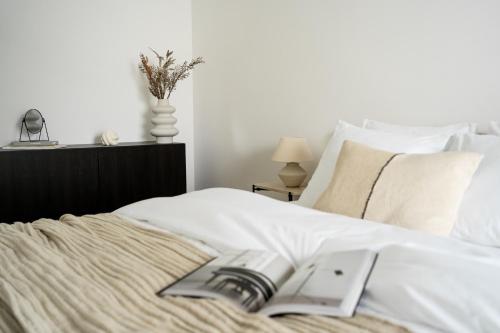 um quarto com uma cama branca com um livro em Unique & Modern Apartment Zabłocie na Cracóvia