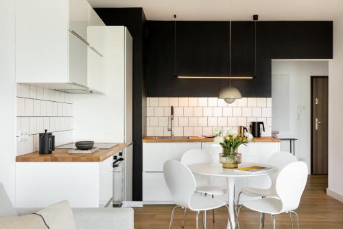 a kitchen with a white table and white chairs at Unique & Modern Apartment Zabłocie in Kraków