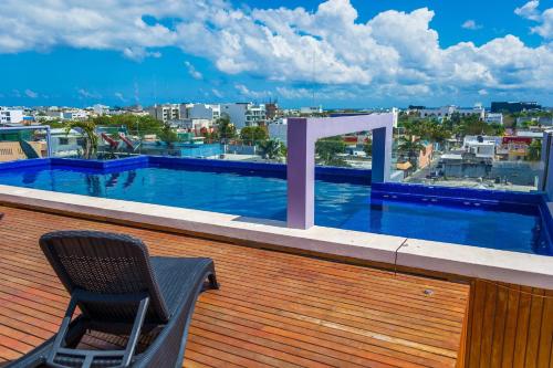 a chair on a balcony with a swimming pool at Playa Centro Rooftop Apartments & Studios in Playa del Carmen