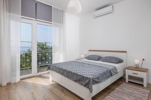 een witte slaapkamer met een bed en een balkon bij Apartment Div in Lovran