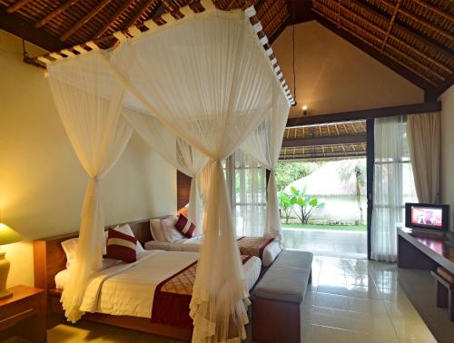 a bedroom with a canopy bed with a television in it at Pertiwi Resort & Spa in Ubud