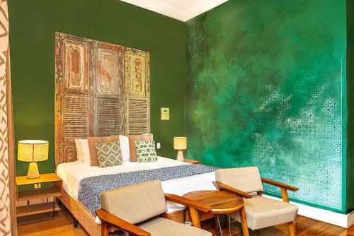 a bedroom with a bed and two chairs and a painting at Selina Lapa Rio de Janeiro in Rio de Janeiro