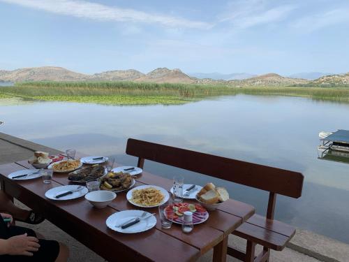 een tafel met voedsel erop naast een lichaam water bij Lake Skadar Paradise in Podgorica