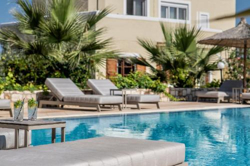 uma piscina com espreguiçadeiras e um hotel em Elea Suites & Residences em Gouves