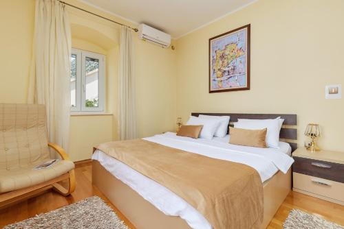 a bedroom with a large bed and a chair at Konoba 224 Apartments in Kotor