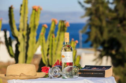 a bottle of wine on a table with a hat and glasses at Nicos Studios & Apartments in Logaras