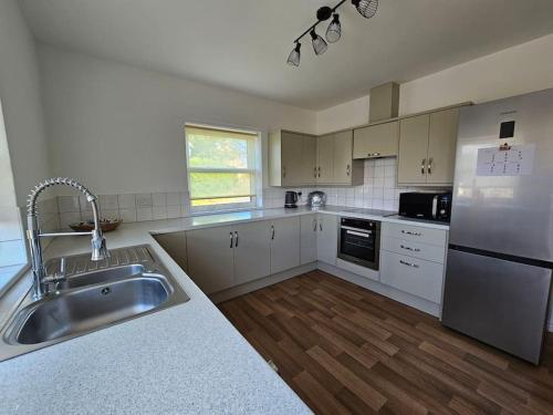 a large kitchen with a sink and a refrigerator at Ravensworth Cottage in Ravensworth