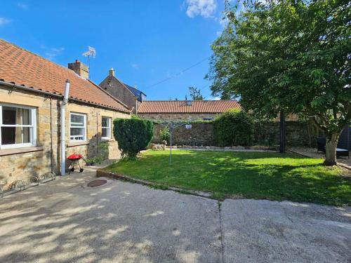 a house with a yard with a yard at Ravensworth Cottage in Ravensworth