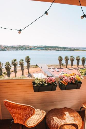 a balcony with two plants and chairs and a view of the water at Golden Place - Seixal in Arrentela