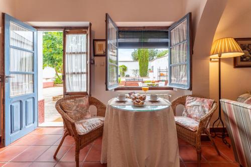 uma sala de jantar com mesa, cadeiras e janelas em Casa Rural con piscina- Tierra de Barros 