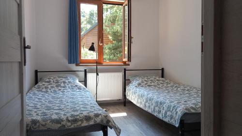 two beds in a room with a window at Apartamenty Pod Lasem in Ostrowo
