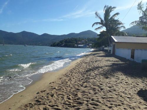 una playa de arena con un edificio y una palmera en Casa praia 4 quartos Sul da Ilha Florianópolis, en Florianópolis