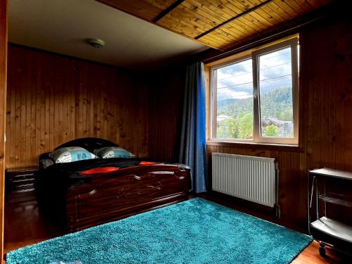 a bedroom with a bed with a window and a blue rug at Приват-котедж Зарінок in Mykulychyn