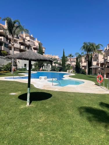 a swimming pool with an umbrella in the grass at Bermeja view apartment in Manilva