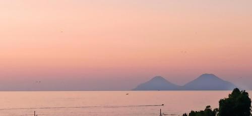 a sunset over the water with mountains in the background at Aeolian view in Piraino