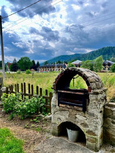 a stone oven in a field next to a fence at Приват-котедж Зарінок in Mykulychyn