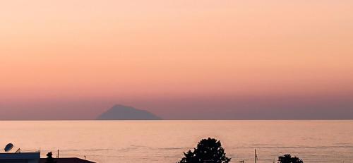 a sunset over the water with a mountain in the background at Aeolian view in Piraino