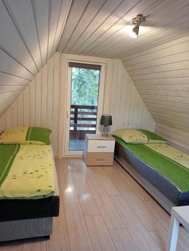 a room with two beds and a window at Domek Pod Sosnami D in Krasnobród