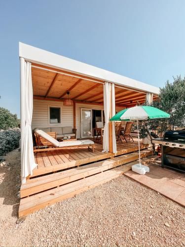 a house with a wooden deck with an umbrella at Diamond Coast Mobile Home in Drage