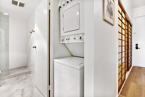a white laundry room with a washer and dryer at Hale Mahina A103 in Kahana