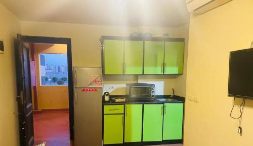 a kitchen with green cabinets and a refrigerator at Chalet golf porto marina in El Alamein
