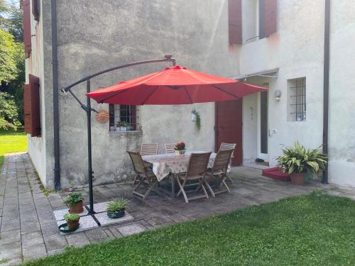 uma mesa e cadeiras sob um guarda-sol vermelho num pátio em Al Rustico em Bassano del Grappa