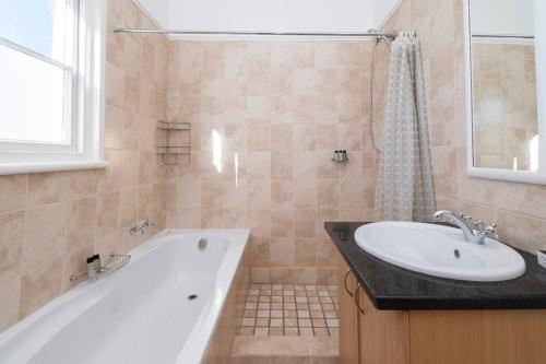 y baño con bañera blanca y lavamanos. en Enchanting Abode in Rosebank, en Ciudad del Cabo