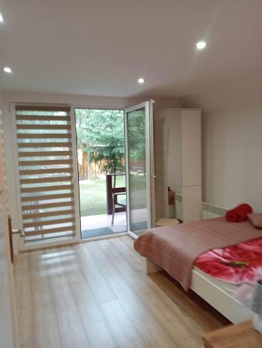 a bedroom with a bed and a sliding glass door at DOMEK POD SOSNAMI in Krasnobród