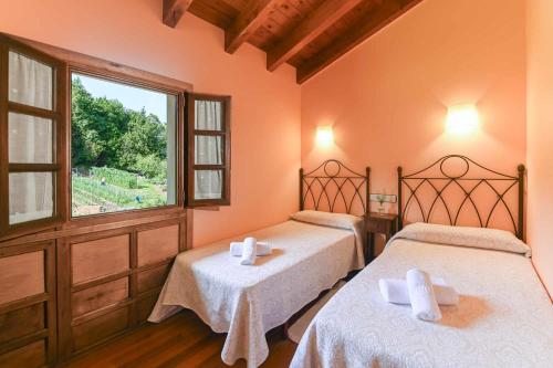 two beds in a room with a window at Apartamentos Rurales El Cuetu in Picones