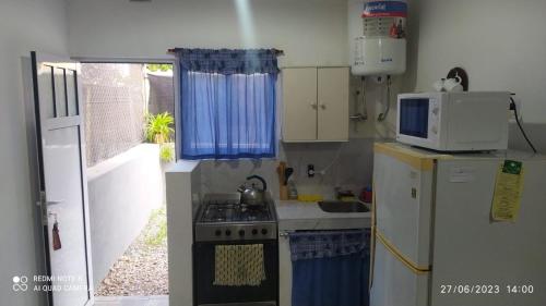 a small kitchen with a stove and a microwave at Departamentos Rosales in Valeria del Mar