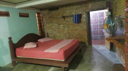 a bedroom with a bed in a room with a brick wall at Sumatra Jungle Trek In & Orangutan Trips in Bukit Lawang