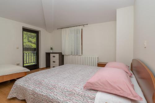 a bedroom with a bed with pink pillows and a window at Apartman Marin in Makarska