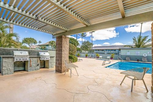 an outdoor patio with a fireplace and a swimming pool at Kihei Bay Surf 245 in Kihei