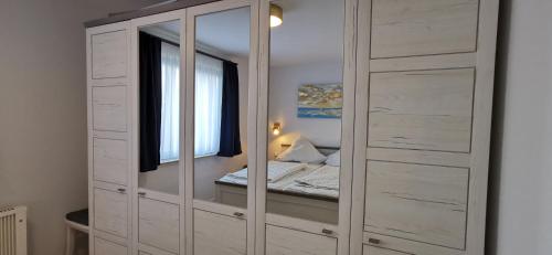 einen großen weißen Schrank mit Spiegeln in einem Schlafzimmer in der Unterkunft Achtern Diek in Horumersiel