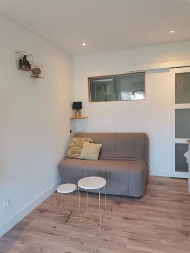 un salon avec un canapé et deux tables dans l'établissement Studio COSY avec terrasse St Barthélémy, à Saint-Barthélemy-dʼAnjou