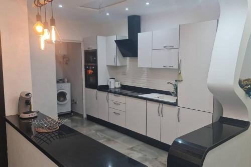 eine Küche mit weißen Schränken und einer schwarzen Arbeitsplatte in der Unterkunft bel appartement de vacances in Saidia 