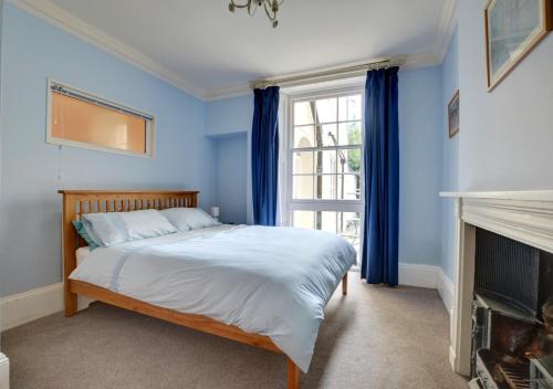 a bedroom with a bed with blue walls and a fireplace at Conkers in Swanage