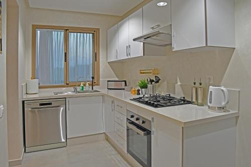 a kitchen with white cabinets and a stove top oven at AKS Home appart 1 - CABONEGRO in Cabo Negro