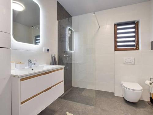 Un baño blanco con lavabo e inodoro. en Domek Leniuchowo, en Rabka