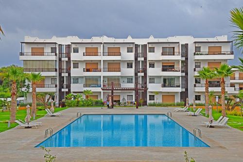 a large apartment building with a swimming pool and palm trees at AKS Home appart 1 - CABONEGRO in Cabo Negro