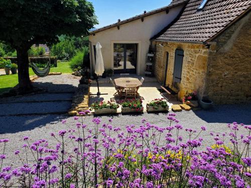 a garden with a table and flowers in front of a building at Le Pech de Vigne in Bio