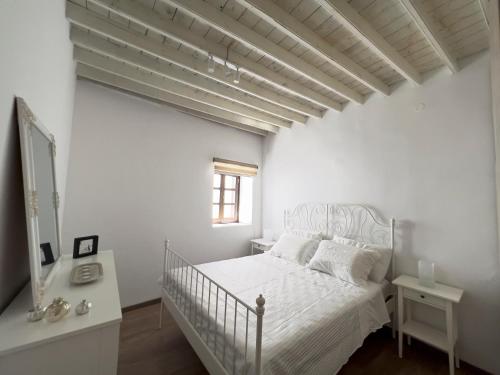 een witte slaapkamer met een bed en een raam bij Villa AleNi Lindos in Lindos