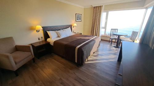 een hotelkamer met een bed, een stoel en een raam bij Hotel Diego de Almagro Valparaíso in Valparaíso