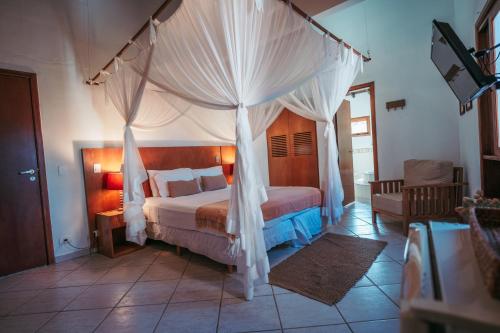 1 dormitorio con 1 cama con dosel en Pousada Brigitte, en Barra do Sahy