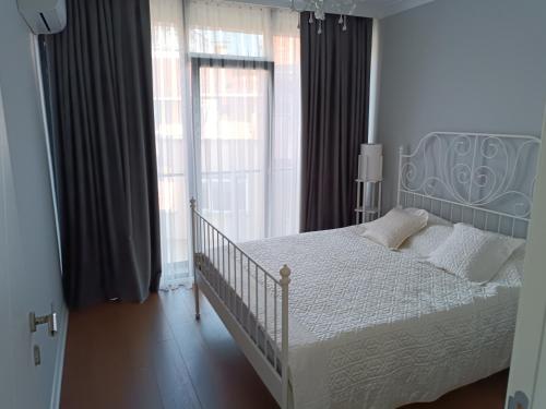 een slaapkamer met een wit bed en een groot raam bij BAOF residence in Istanbul