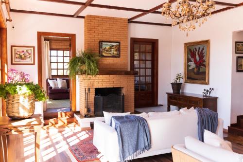a living room with a white couch and a fireplace at Pousada Hortelã Village in Campos do Jordão